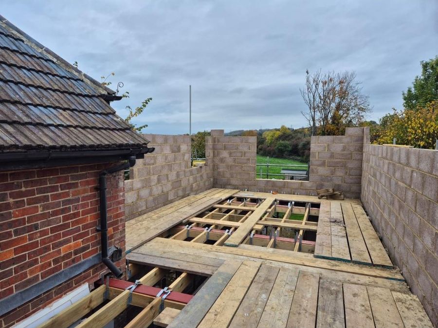 Floor structure in — Steel and timber floor joists spanning a new room, open to a rural outlook.
